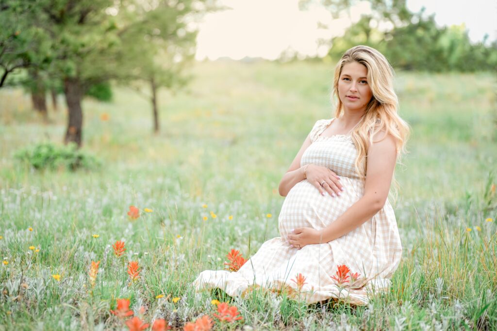 Pregnant woman maternity session sitting in a field of flowers in southern colorado 