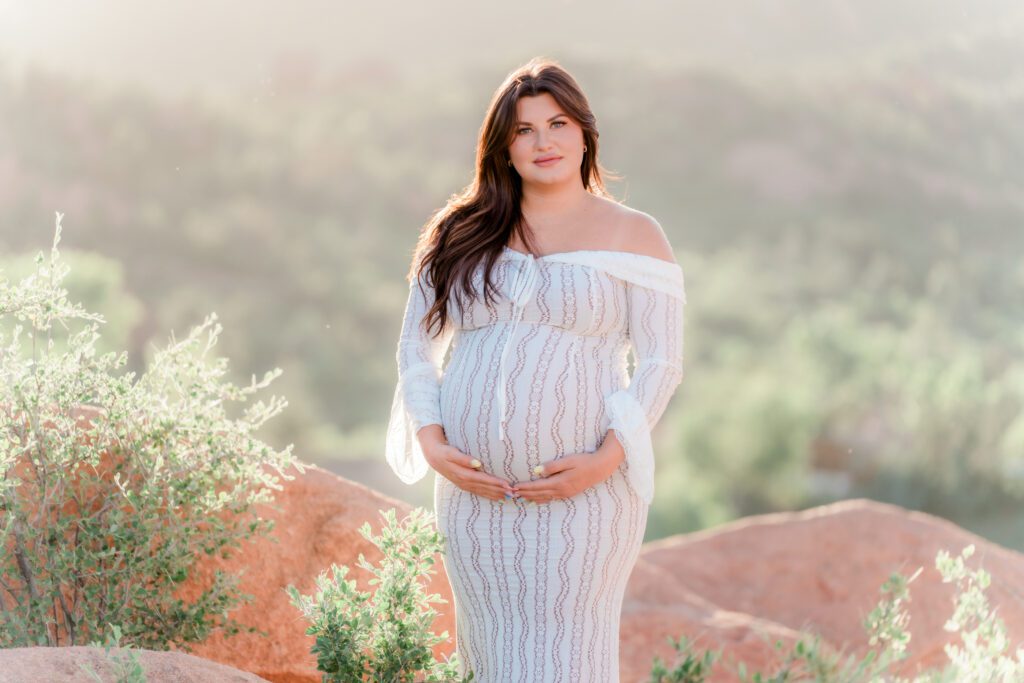 Pregnant woman in white dress maternity session at the garden of the gods, colorado 